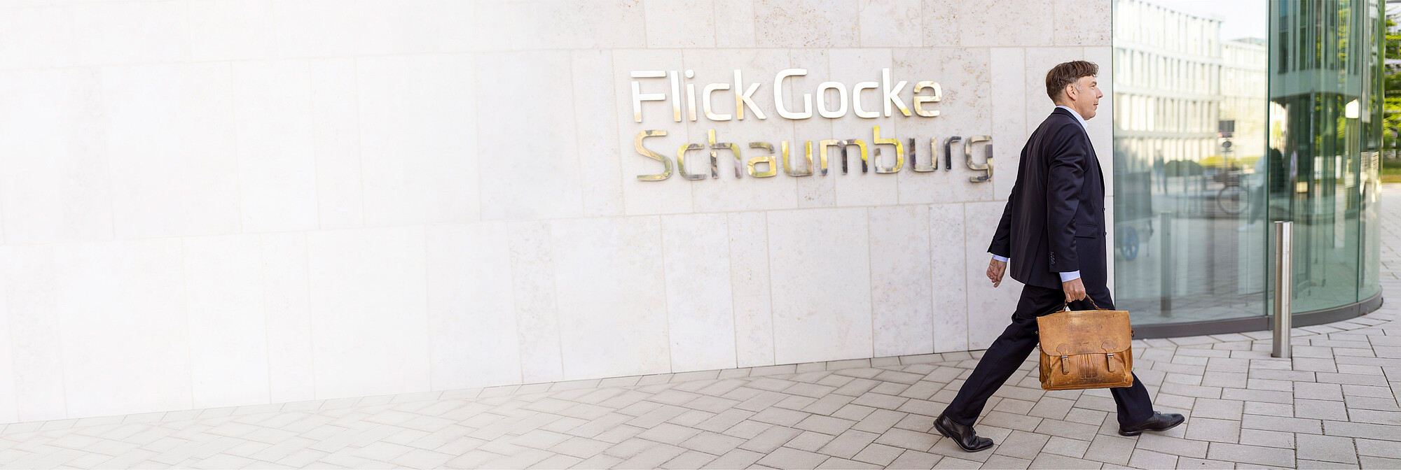 Mann geht an Eingang mit Flick-Gocke-Schaumburg-Logo vorbei